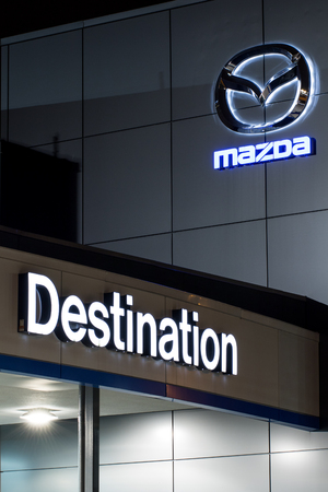 Vancouver. Canada - January 9, 2018: Mazda logo on the facade of official dealer office. Mazda Motor Corporation is a Japanese car brand, automotive manufacturer. Night shot with logos illuminated.のeditorial素材