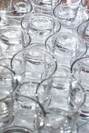 Array of shot glasses on white table - metallic colors. Glasses side by side and reflecting into each other.の写真素材