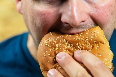 Young man eats delicious appetizing burger.の写真素材