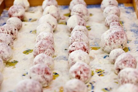 Meat ball in the flour on a tray ready to be cookedの写真素材