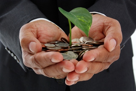 Hispanic man holding a plant in a pile of moneyの写真素材