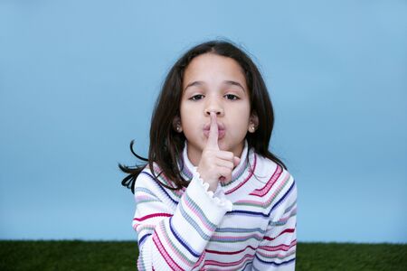 Girl giving the quiet sign with her finger and mouth