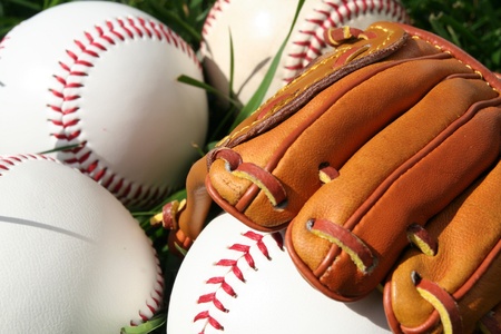 A baseball glove surrounded by balls on a field