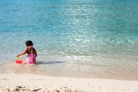 Young girl playing in the sand at the beach with a bucketの写真素材