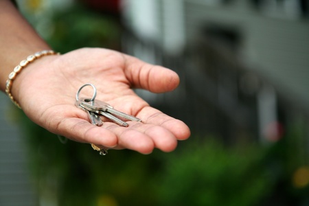 Woman is handing keys to the cameraの写真素材