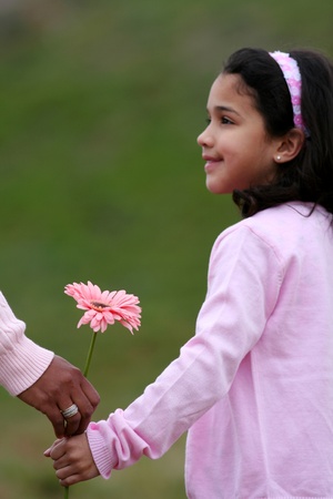 Girl with her mother holding a new flowerの写真素材