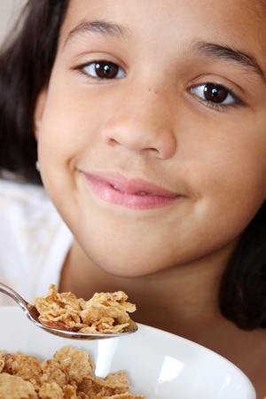 Girl eating her breakfast sitting at the tableの写真素材