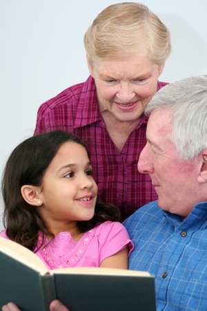 Grandfather and Grandmother reading a book to his granddaughter