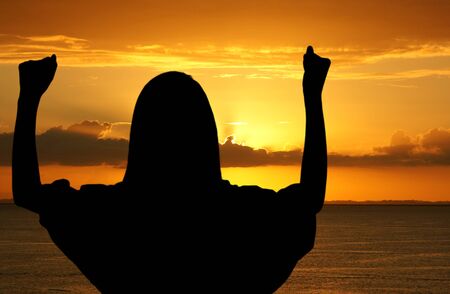 Girl with hands up while standing on the beachの写真素材