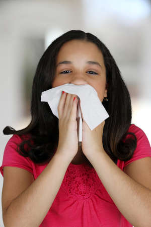 Teenage girl blowing her nose with tissueの写真素材