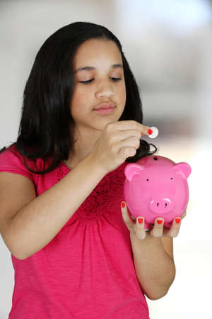 Teen girl putting money in her piggy bankの写真素材