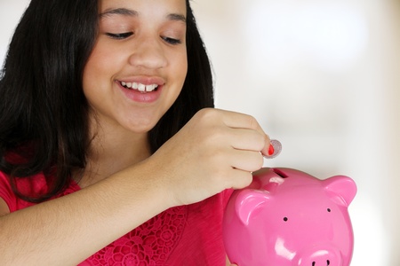 Teen girl putting money in her piggy bankの写真素材