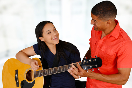 Teenage girl playing the guitar on a white background