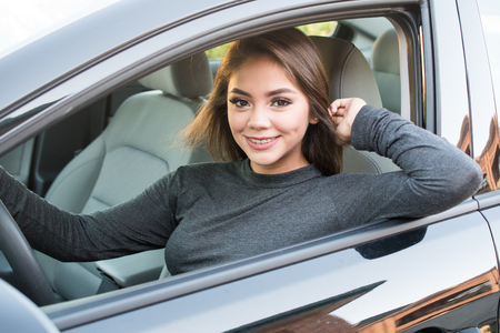 Happy teen girl driving a new carの写真素材