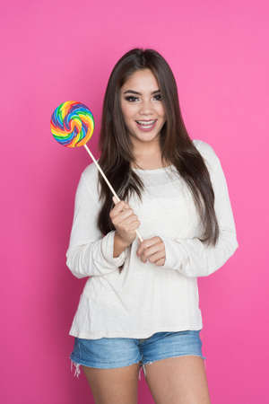 Happy teen hispanic girl on pink backgroundの写真素材