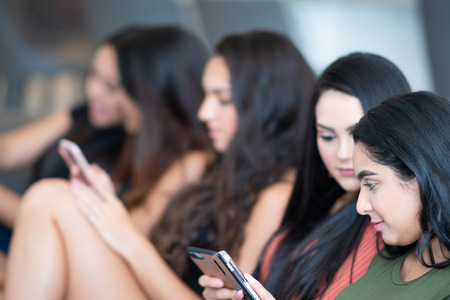 Group of five teen girls using their smart phonesの写真素材