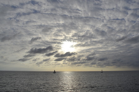 Picture of two sailboats under a partially covered  sun sailing the Pacificの写真素材