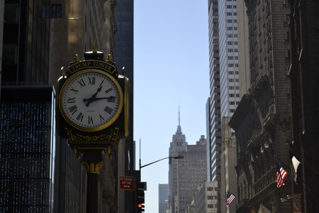 Clock in 5th avenue with the Empire State Building on the backgroundの写真素材