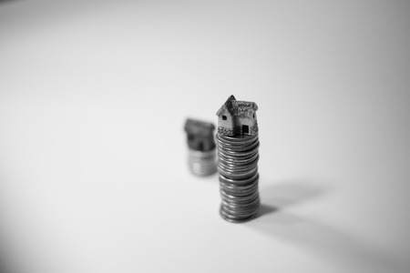 Miniature houses on top of piles of coins to represent differences in prizesの写真素材