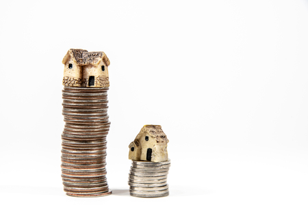 Miniature houses on top of piles of coins to represent differences in prizesの写真素材