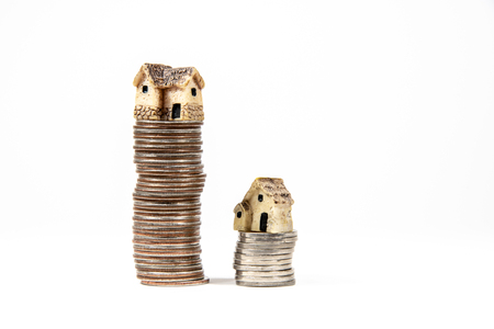 Miniature houses on top of piles of coins to represent differences in prizesの写真素材