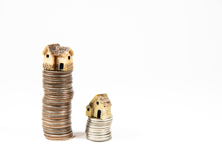 Miniature houses on top of piles of coins to represent differences in prizesの写真素材