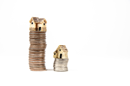 Miniature houses on top of piles of coins to represent differences in prizesの写真素材