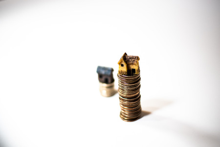Miniature houses on top of piles of coins to represent differences in prizesの写真素材