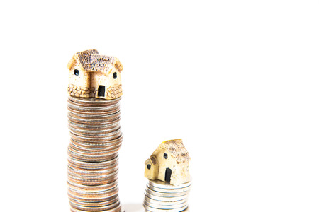 Miniature houses on top of piles of coins to represent differences in prizesの写真素材