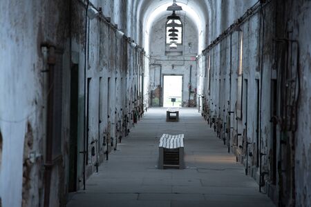 One of the wings of an abandoned penitentiary with the entrance to small cells on both sidesの写真素材