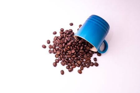 Coffee beans spilled from a mug isolated over a white backgroundの写真素材