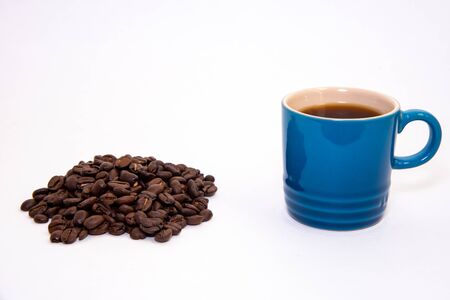 Blue porcelain cup filled with coffee close to a group of coffee beansの写真素材
