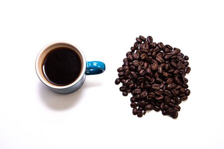 Blue porcelain cup filled with coffee close to a group of coffee beansの写真素材
