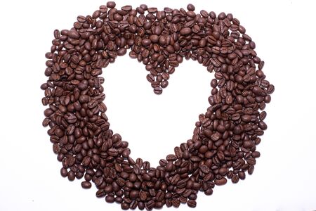Heart frame formed by coffee beans over a white backgroundの写真素材