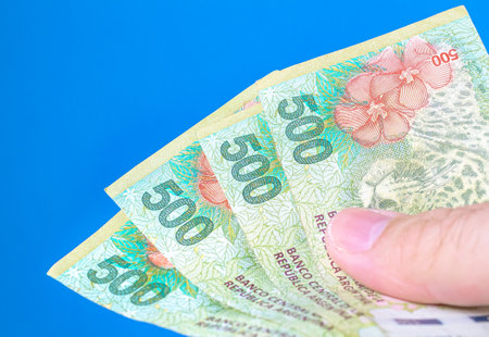 A person holding pesos bills of the money of the argetine currency, the Argentine peso, isolated on...