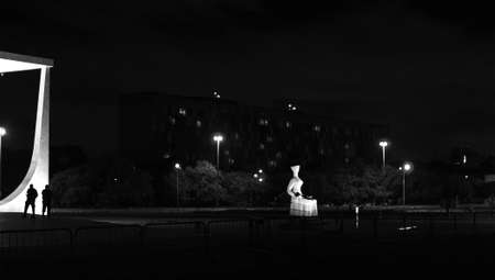 Silhouette of a woman sitting on a bench in the center of Bucharest at night.の写真素材