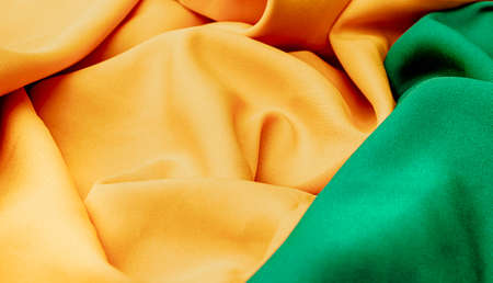Texture, background, pattern. Yellow and green satin fabric is crumpled.
