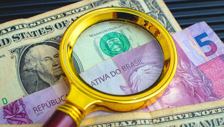 Magnifying glass on the background of dollar bills and banknotes.
