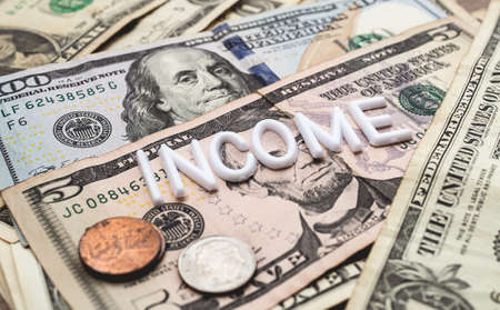 Money and the word Income on the background of dollar bills. Business concept