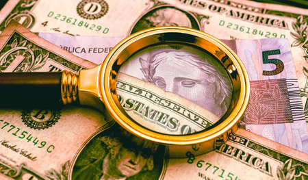 Magnifying glass on the background of dollar bills. Business concept.