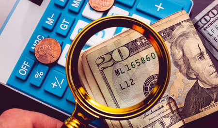 Dollars and calculator with a magnifying glass. Business conceptの写真素材