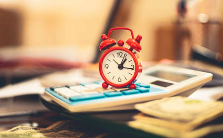 Time is money. Alarm clock and calculator on the table.