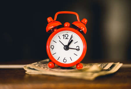 Time is money. Alarm clock and money on the table.の写真素材