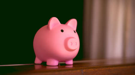 Pink piggy bank on a wooden table against a green background.の写真素材