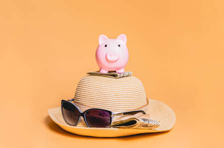 Pink piggy bank wearing a straw hat, sunglasses on an orange backgroundの写真素材