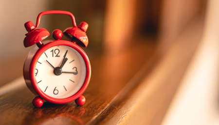 Red alarm clock on a wooden table. Time is running out.の写真素材