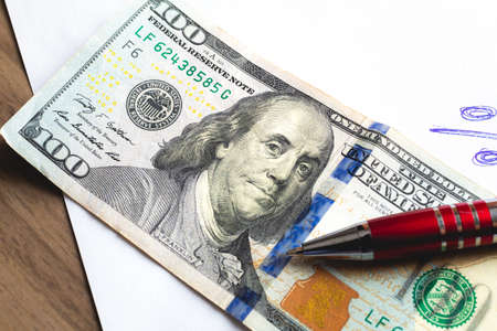 One hundred dollar bills and a pen on the table. Close-up.の写真素材