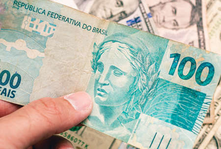 Close-up of a man's hand holding a banknote of 100 rubles.