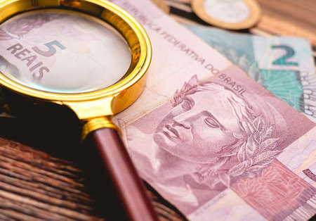 Money and magnifying glass on wooden background. Close-up.の写真素材