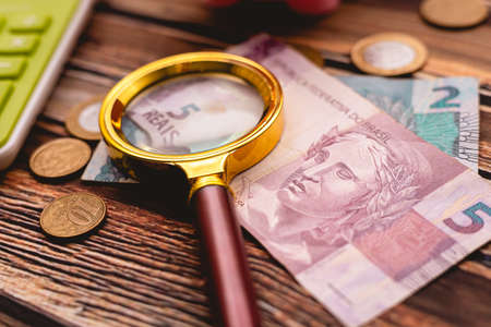 Magnifying glass and banknotes on a wooden table. Business concept